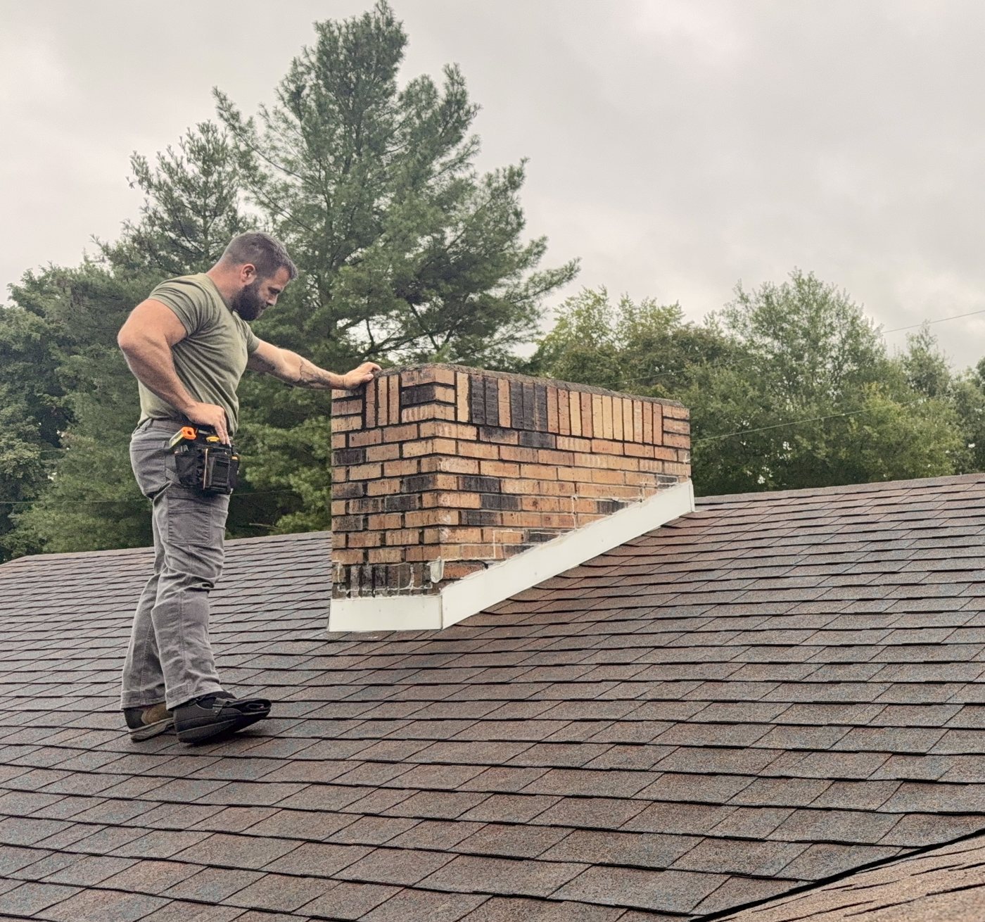 Kyle Peirson inspecting chimney flashing on a shingle roof during a home inspection